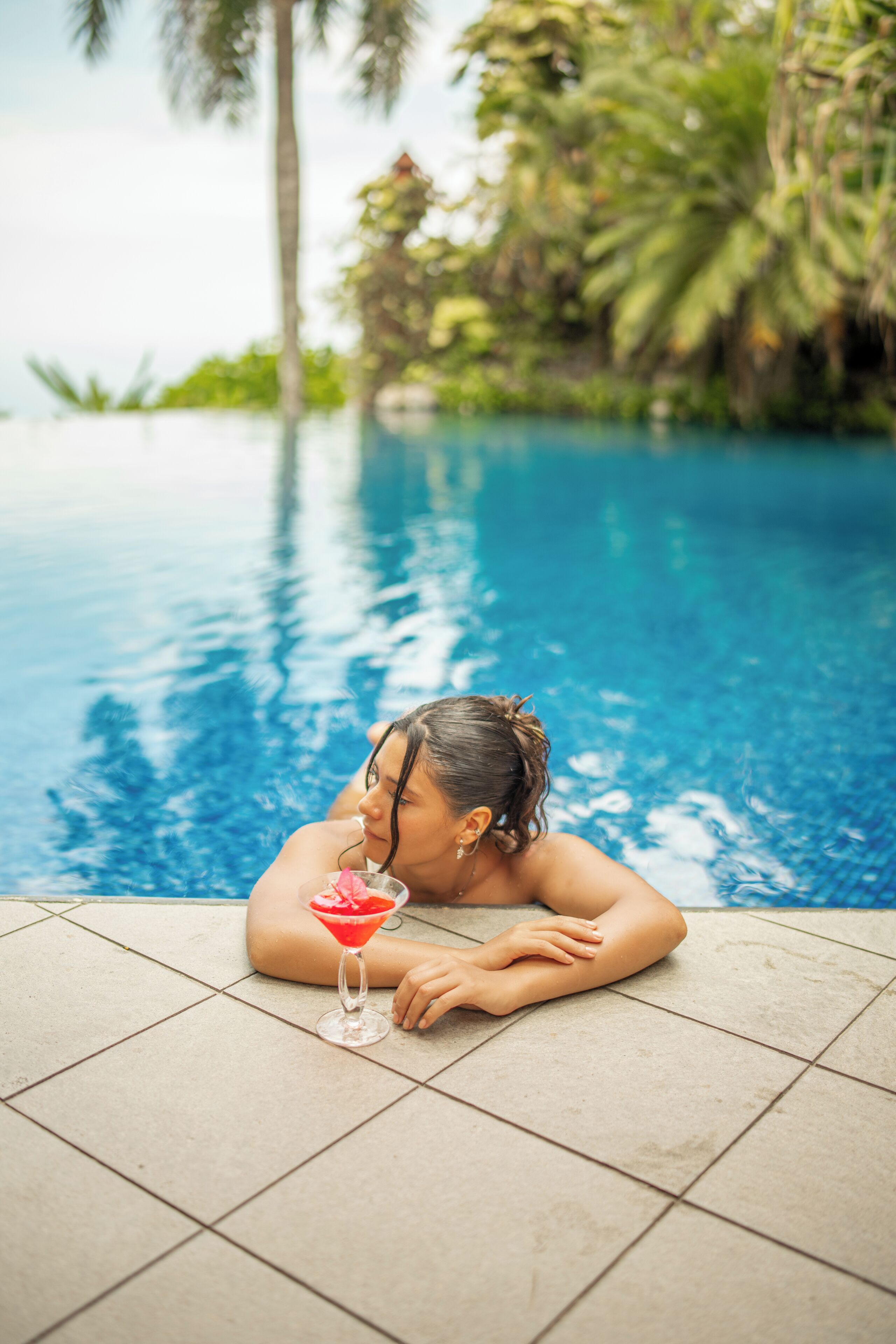 A person relaxing by a pool with a drink.