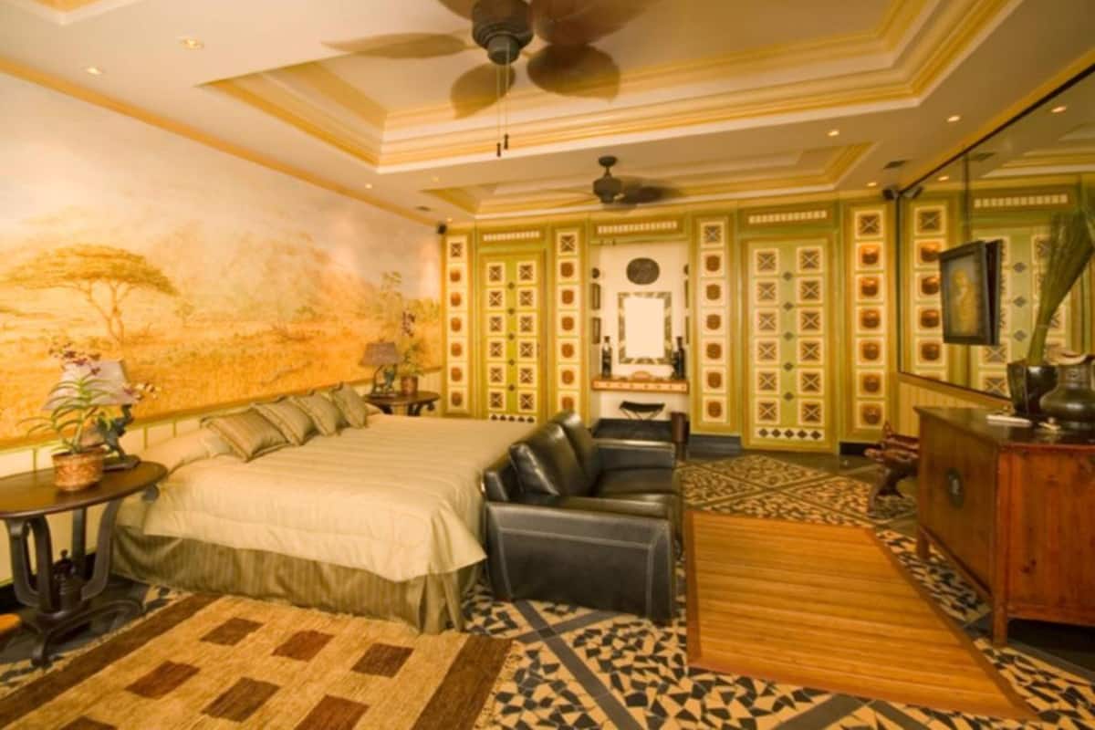 A bedroom with a bed, a sofa, a wooden cabinet, and a ceiling fan.