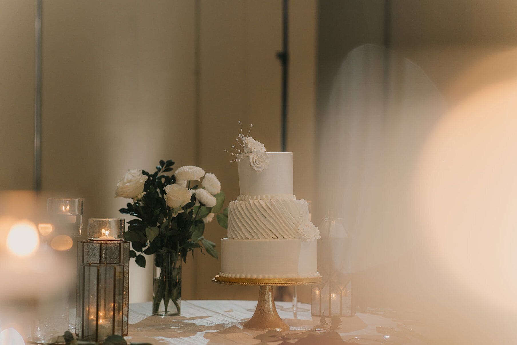 A wedding cake on a table with candles and flowers.