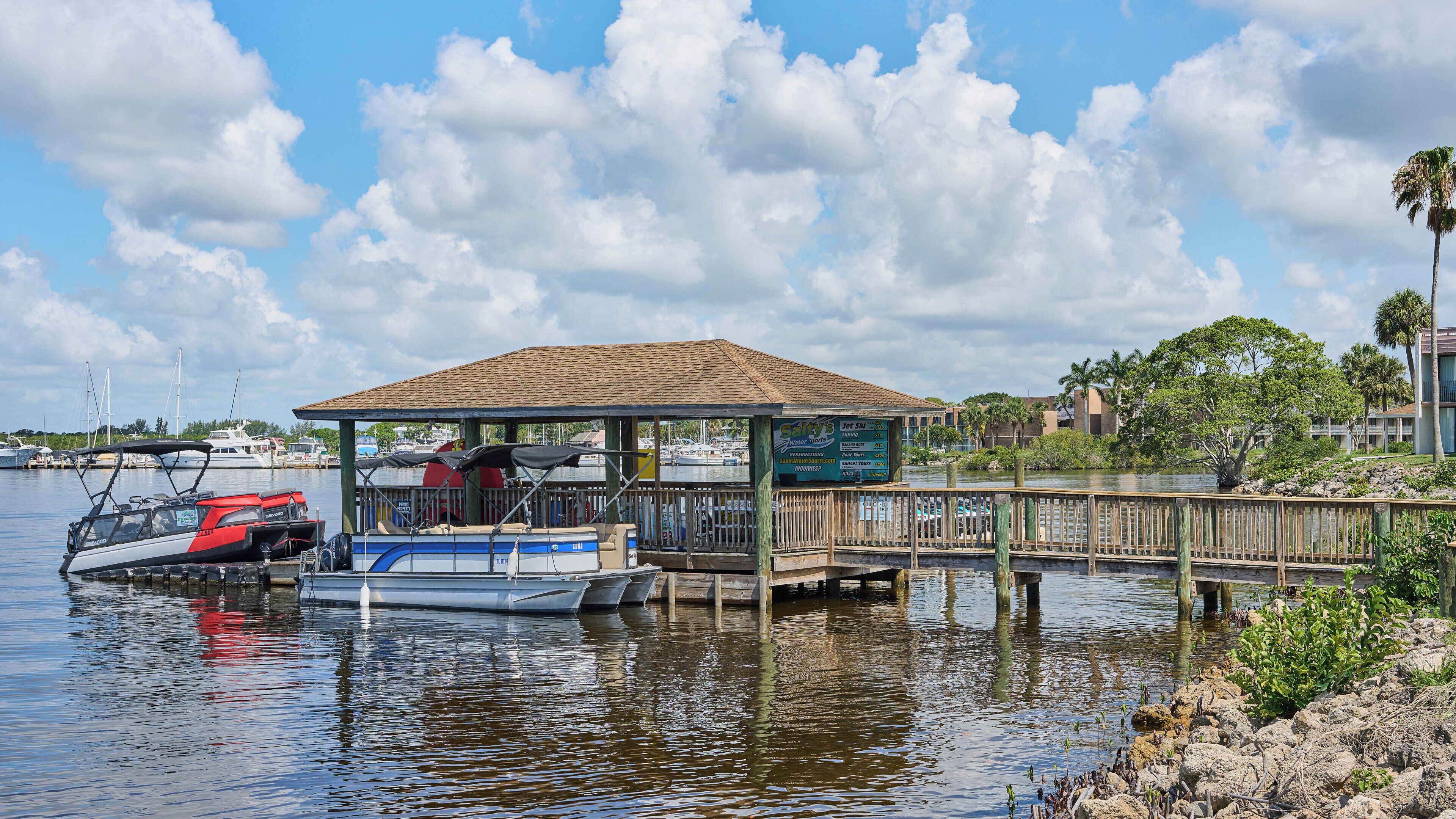 A docked boat, a covered pavilion, and a waterfront view with boats and buildings in the background.