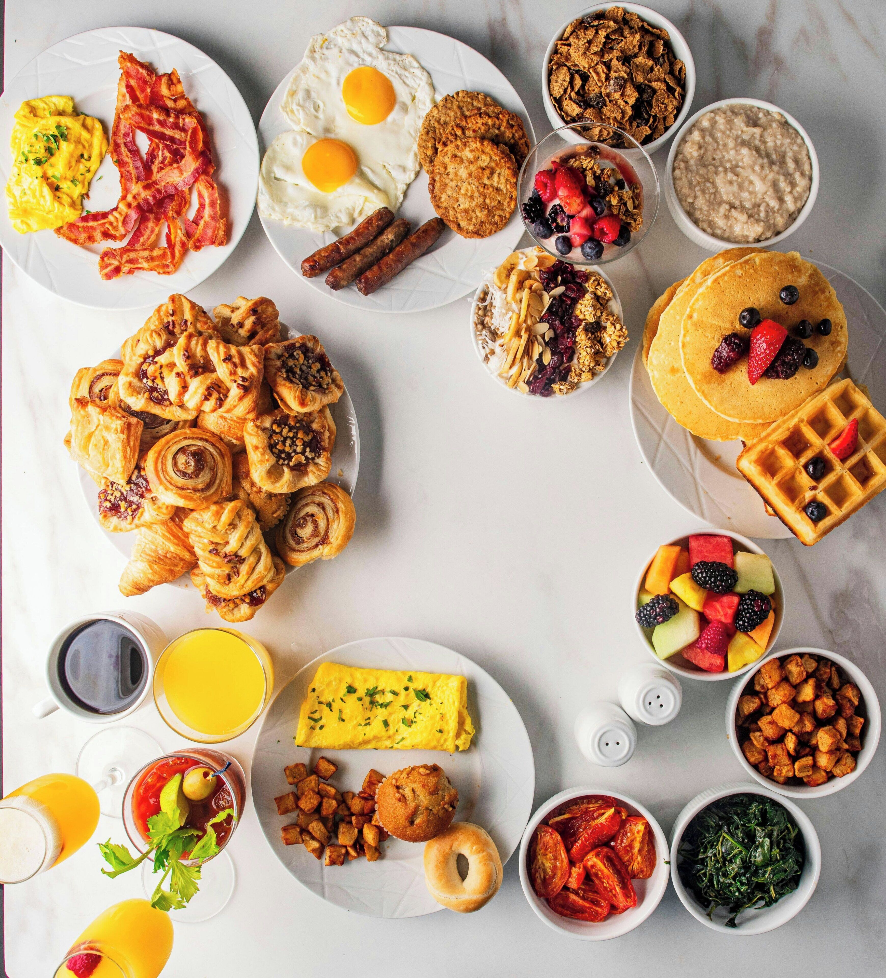 Una mesa con una variedad de platos, incluyendo huevos, pasteles y frutas.