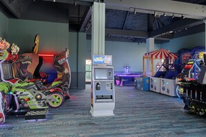 An indoor arcade with various gaming machines, including a motorcycle-themed game and a claw machine. - voco Sandpiper All-Inclusive Resort by IHG (Port Saint Lucie)