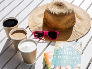 A straw hat, pink sunglasses, and a book titled 'An Island Summer' on a white surface. - voco Sandpiper All-Inclusive Resort by IHG (Port Saint Lucie)