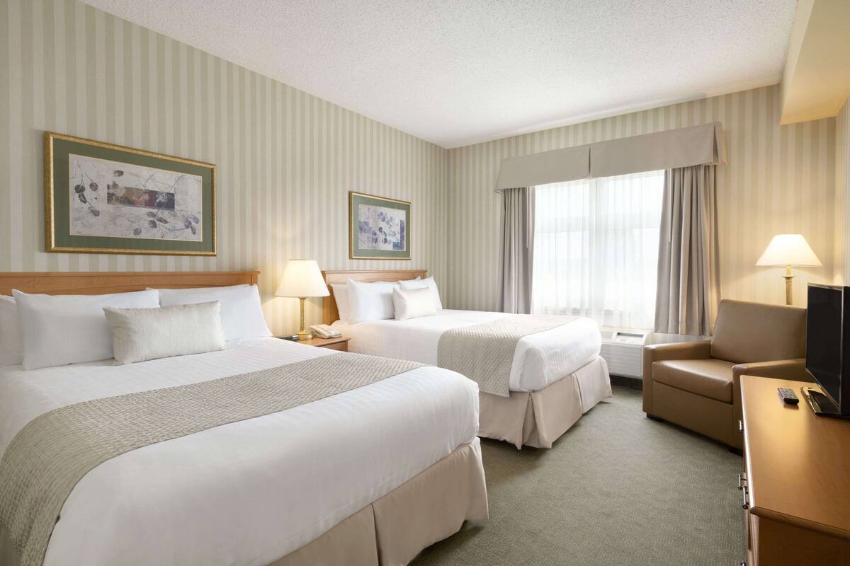 Ein Hotelzimmer mit zwei Betten, einer Schlafcouch, einem Fernseher und zwei Lampen.