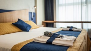 Una habitación de hotel con una cama bien hecha, una mesita de noche y una ventana con cortinas.
