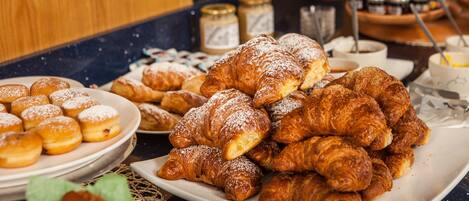 Variedad de pasteles, incluyendo croissants y donas, sobre una encimera.