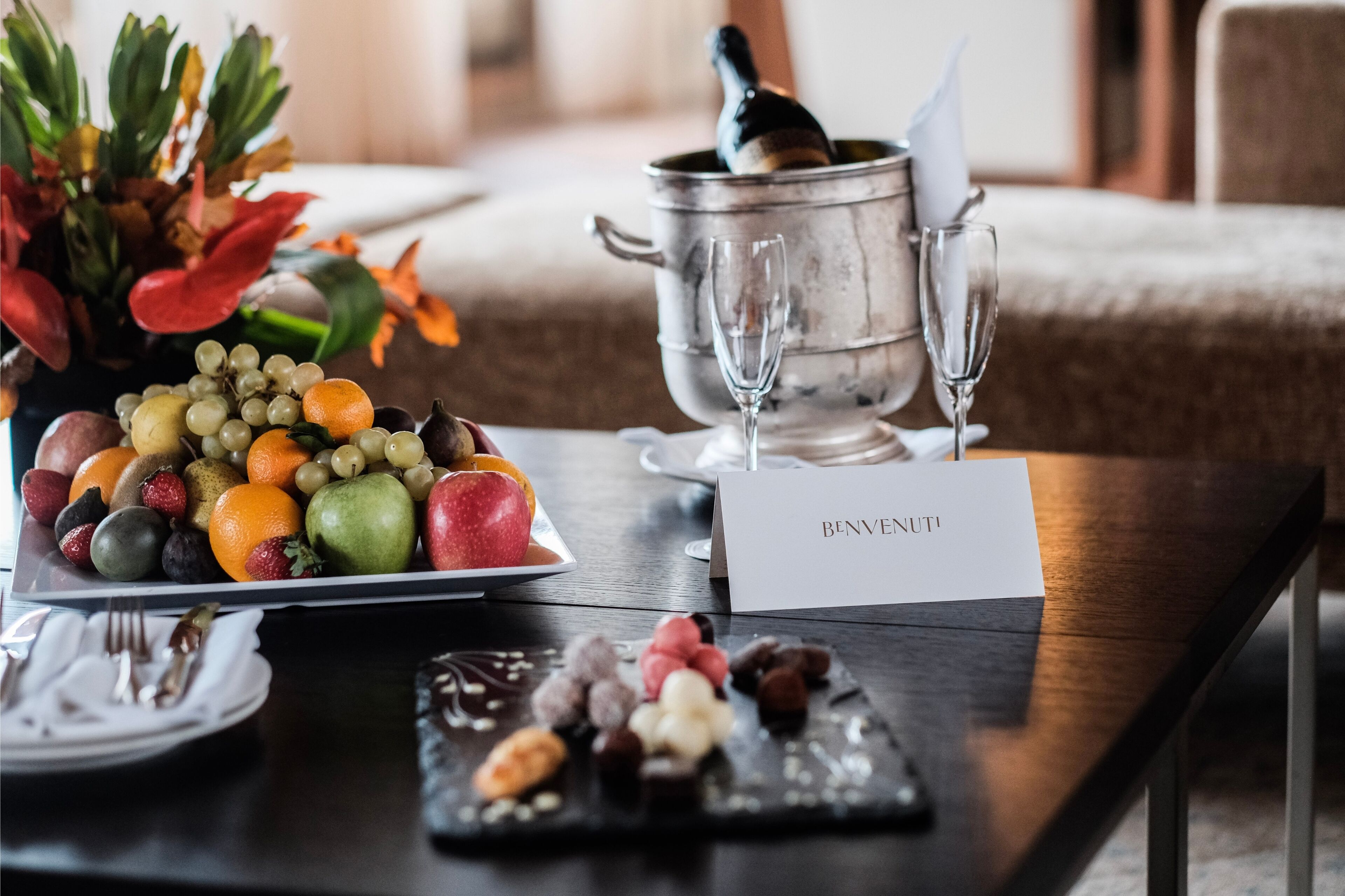 Et bord med et frugtfat, en champagneflaske og et dessertfad.