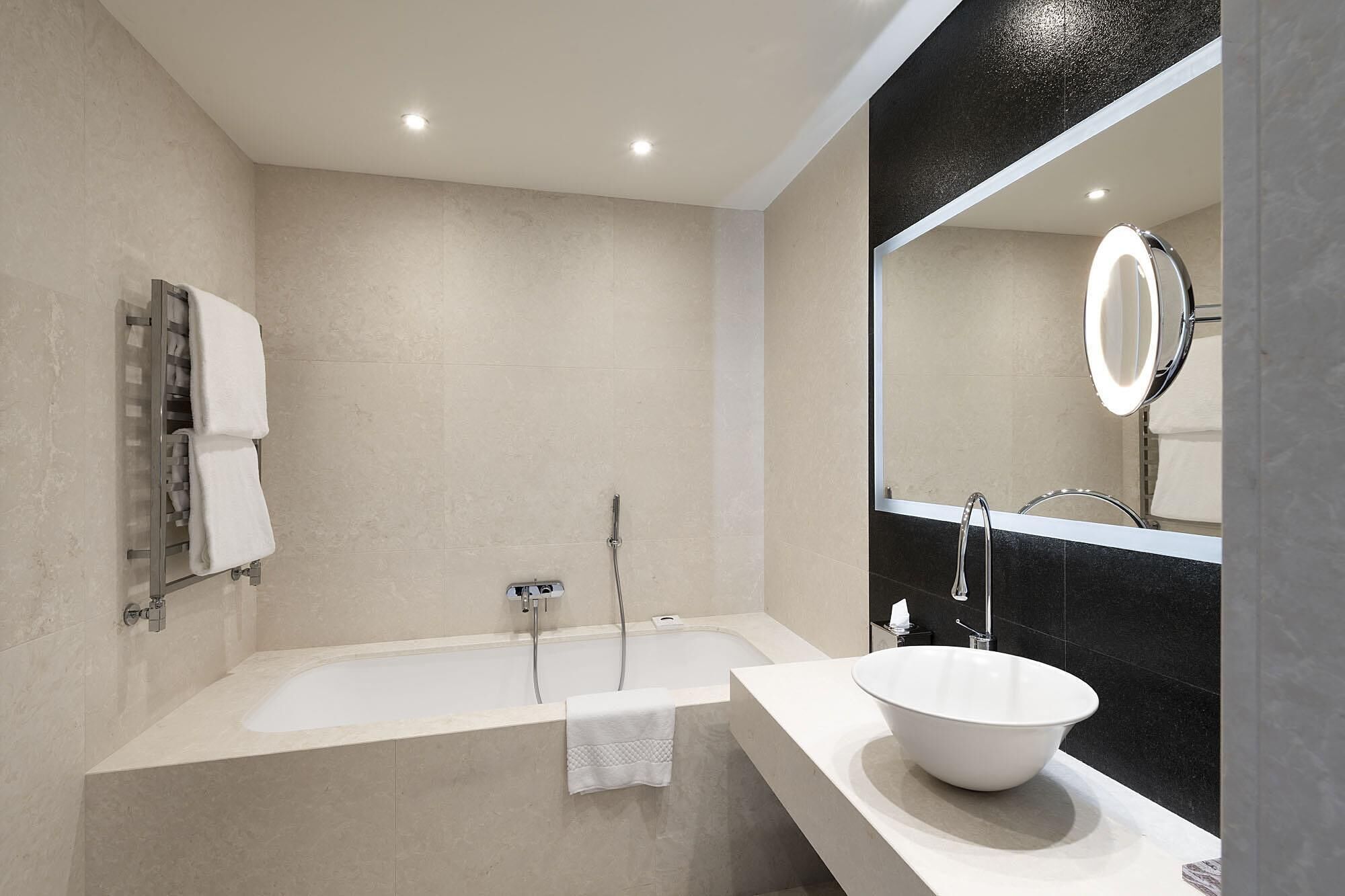 Un bagno moderno con una vasca freestanding, uno specchio grande e un lavandino bianco.