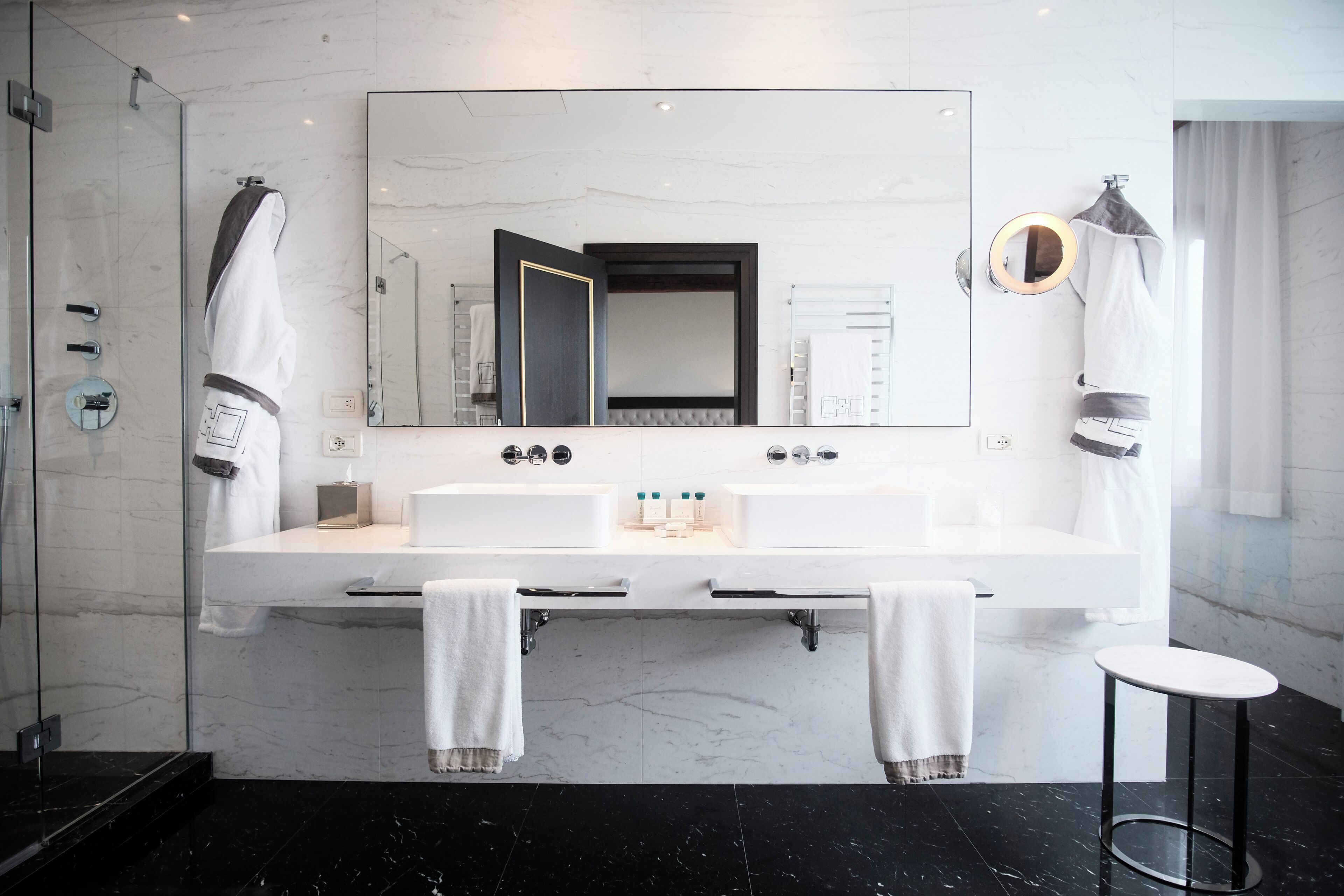 Une salle de bain moderne avec un grand miroir, deux vasques et une douche à l’italienne.