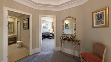 Un couloir avec une coiffeuse, un miroir, un tableau encadré et une chaise.