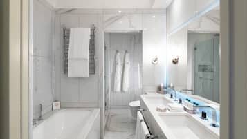 Un baño moderno con bañera, ducha y tocador con un espejo grande.