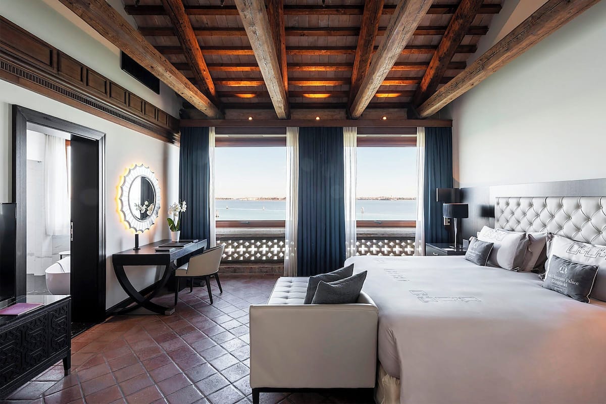A hotel room with a large bed, a desk, and a view of the sea.