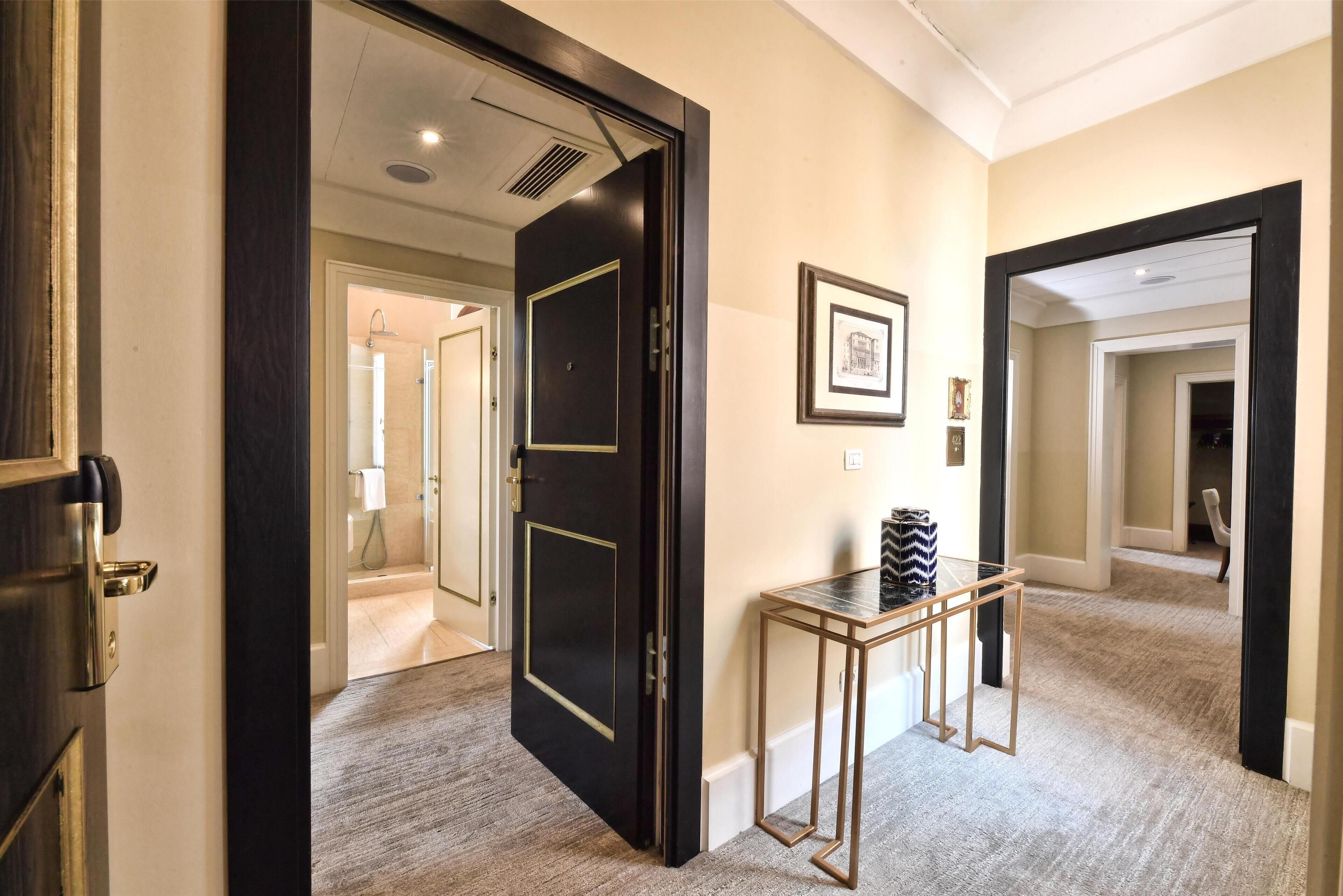 A hallway with a dark wooden door, a small table with a glass top, and a framed picture on the wall.