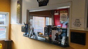 A counter with a 'No Pets Allowed' sign, a 'Sorry, we are not pet friendly' notice, and a 'SORRY NO PETS ALLOWED $100 WILL BE CHARGED' sign. - Travelodge by Wyndham Bay Shore Long Island (Bay Shore)