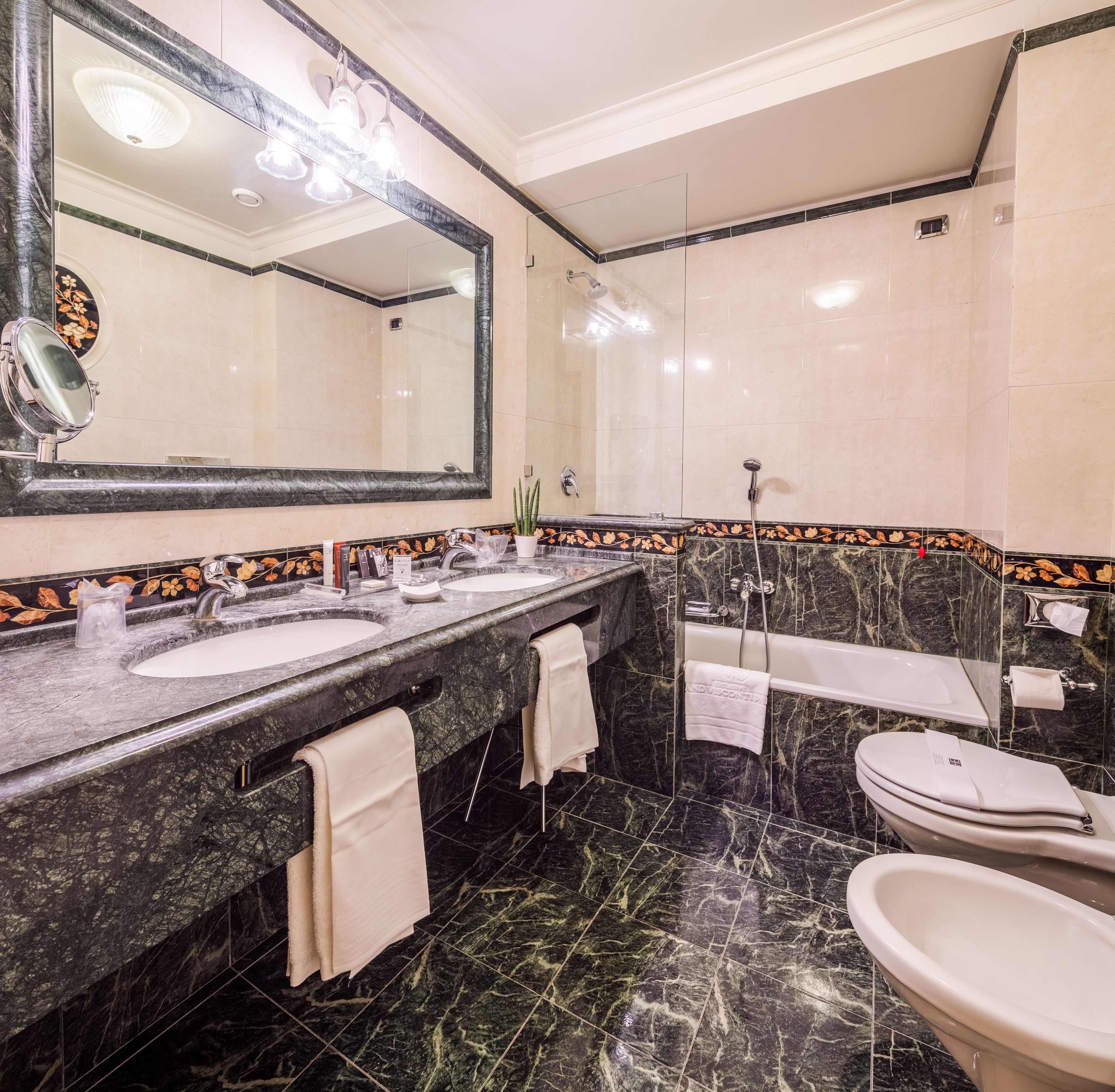 Un baño con dos lavamanos, un espejo grande, una bañera y un inodoro.