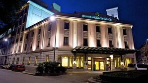 A grand, illuminated building with a sign reading "Grand Vinsonti Palace." - Grand Visconti Palace (Milan)