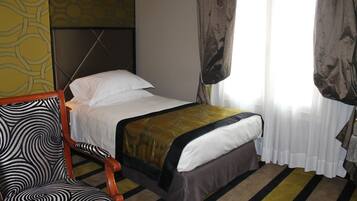 A hotel room with a bed, a chair, and a window with curtains.