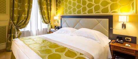 A hotel room with a large bed, a nightstand, and a wall-mounted lamp.