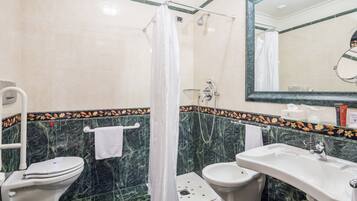 Un bagno con doccia, due servizi igienici, un lavandino e uno specchio.