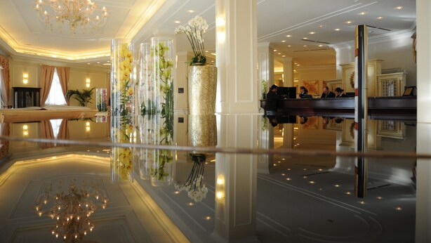 A spacious lobby with a reflective floor, a grand chandelier, and a reception desk with staff. - Grand Visconti Palace (Milan)