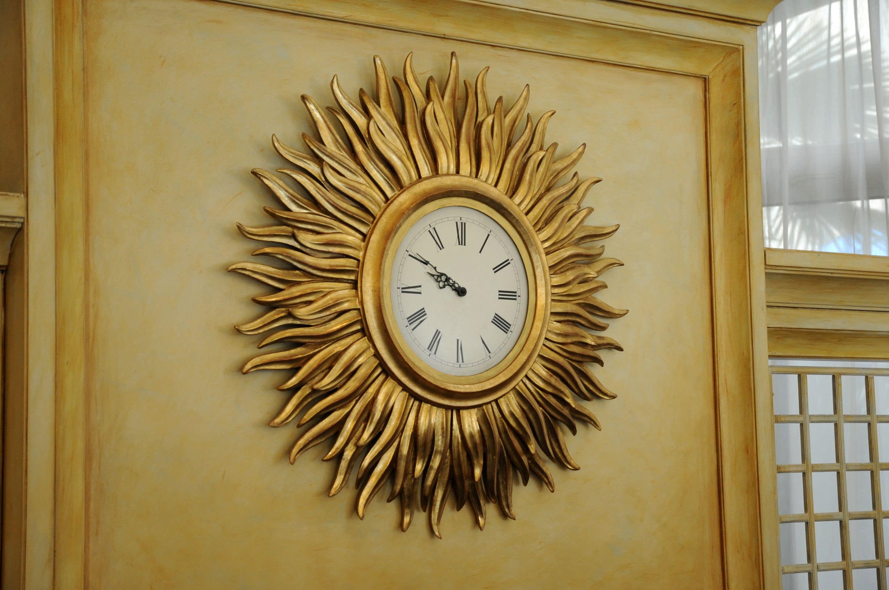 A wall-mounted clock with a sunburst design.