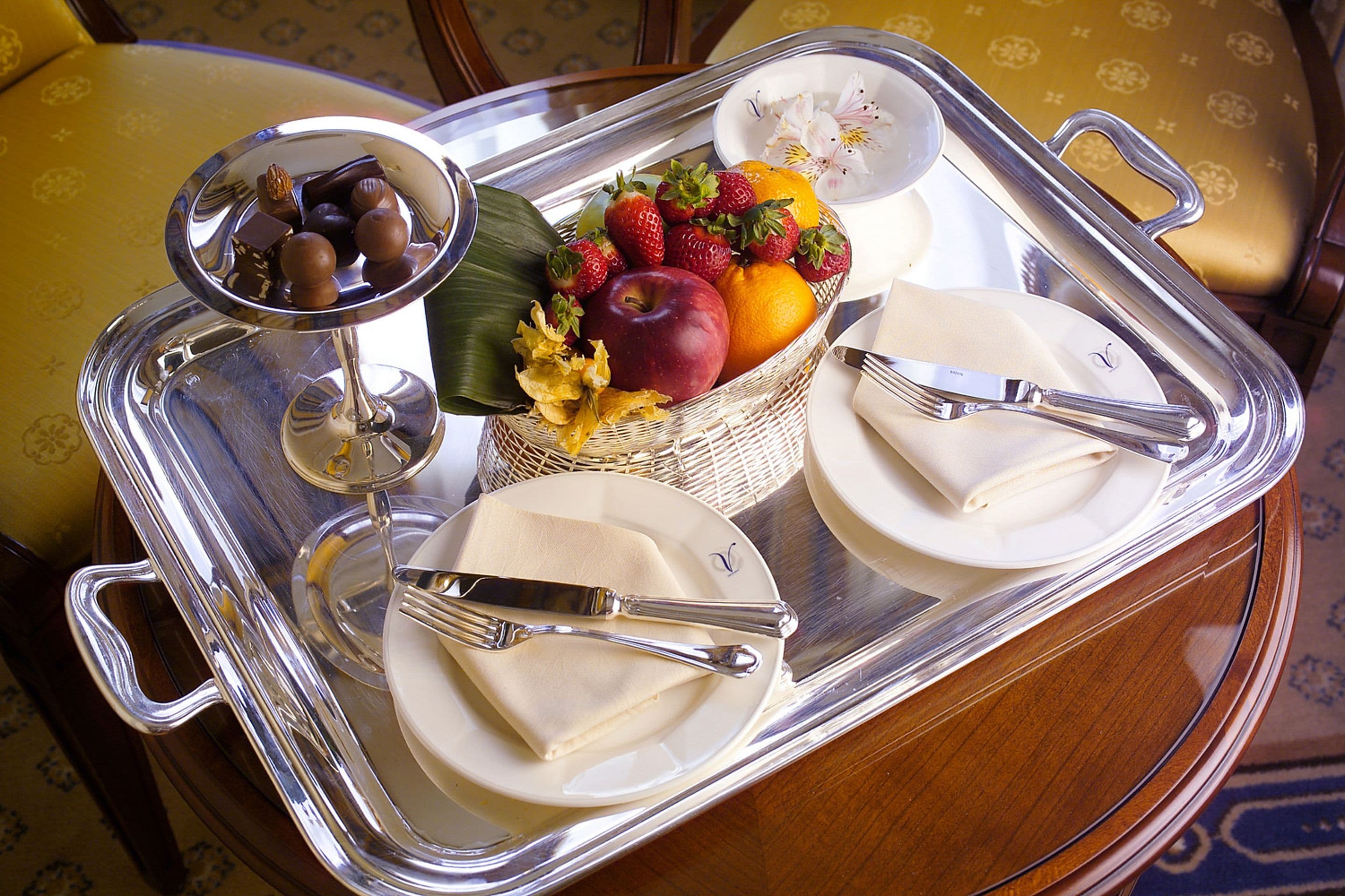 Una bandeja con una cesta de frutas, platos y cubiertos.