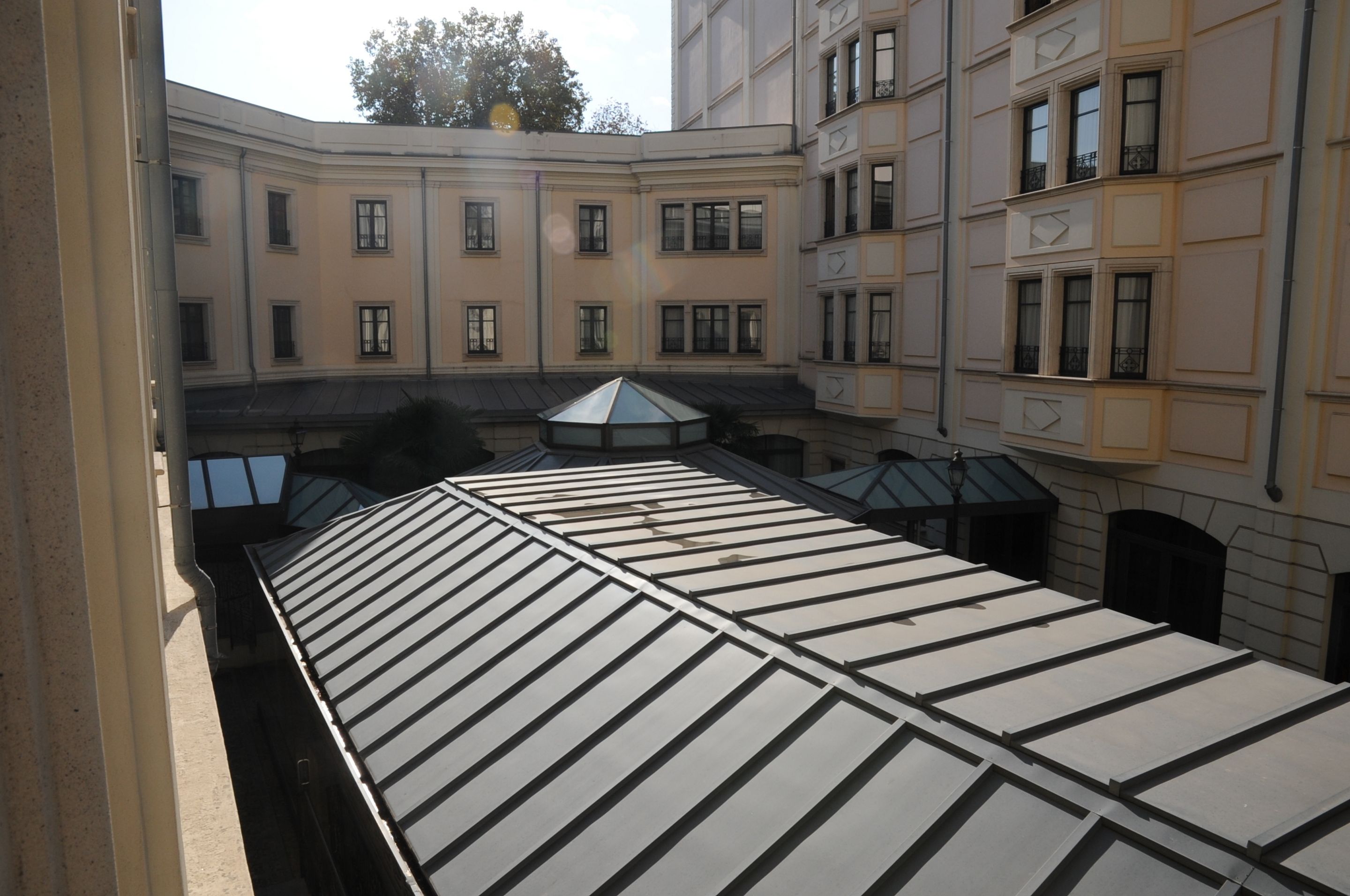 Un cortile con una terrazza coperta, edifici con numerose finestre e una struttura centrale in vetro.