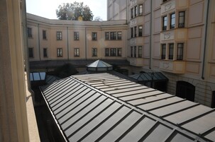 Un cortile con una terrazza coperta, edifici con numerose finestre e una struttura centrale in vetro.