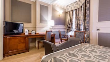 Habitación de hotel con cama, escritorio, televisión y una silla.