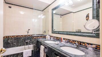 A bathroom with two sinks, a bathtub, and a large mirror.