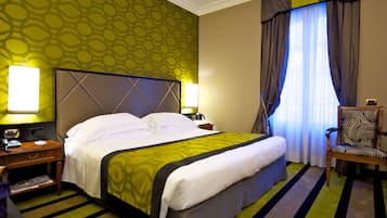 Quarto de hotel com uma cama grande, duas mesas de cabeceira, uma cadeira e uma janela com cortinas.