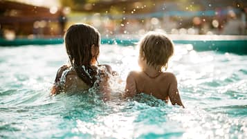 Zwei Personen in einem Schwimmbecken, um sie herum spritzt Wasser.