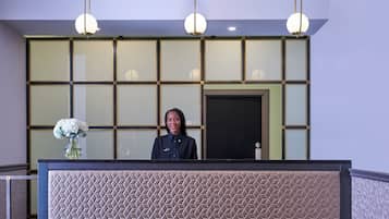 A reception desk with a geometric patterned design, a vase with flowers, and a door in the background.