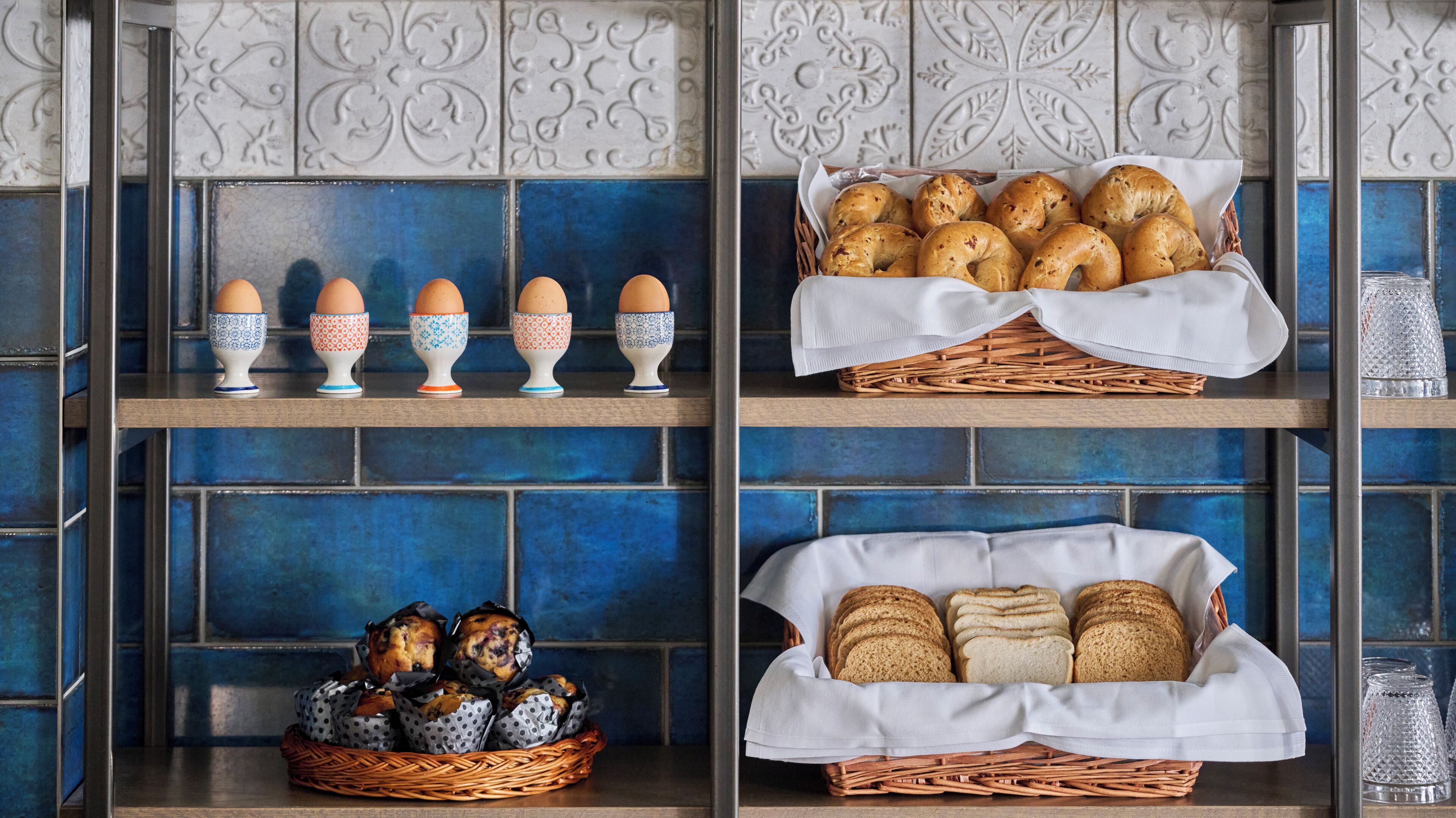 Eine Küche mit blauen Fliesen, Regalen voller Eier, Brot und Gebäck.