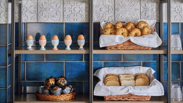 Una cocina con azulejos azules, repisas con huevos, pan y pastelería.