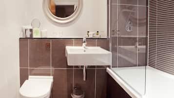 Un baño moderno con inodoro, lavamanos y cabina de ducha con mampara de vidrio.