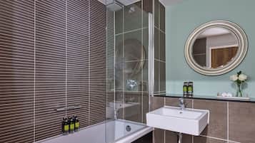 A modern bathroom with a glass-enclosed shower, a white sink, and a mirror with a gold frame.