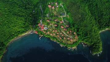 Luftaufnahme eines Küstenresorts mit mehreren Gebäuden mit roten Dächern, einem Schwimmbad und einem kleinen Jachthafen.