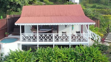 Una casa de dos plantas con techo rojo, un balcón con barandillas blancas y una piscina.