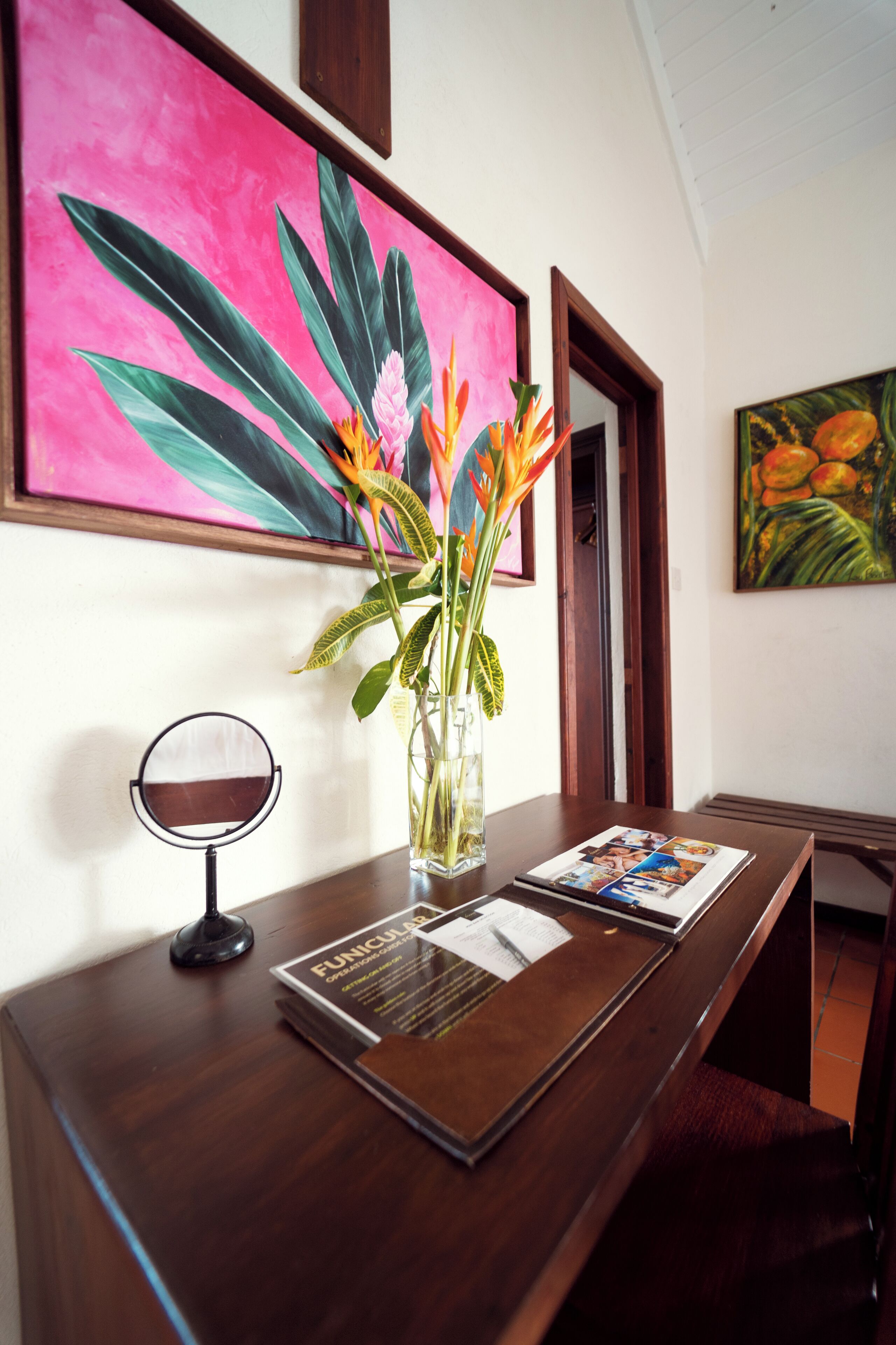 A wooden reception desk with a vase of flowers, a framed picture, and a magazine.
