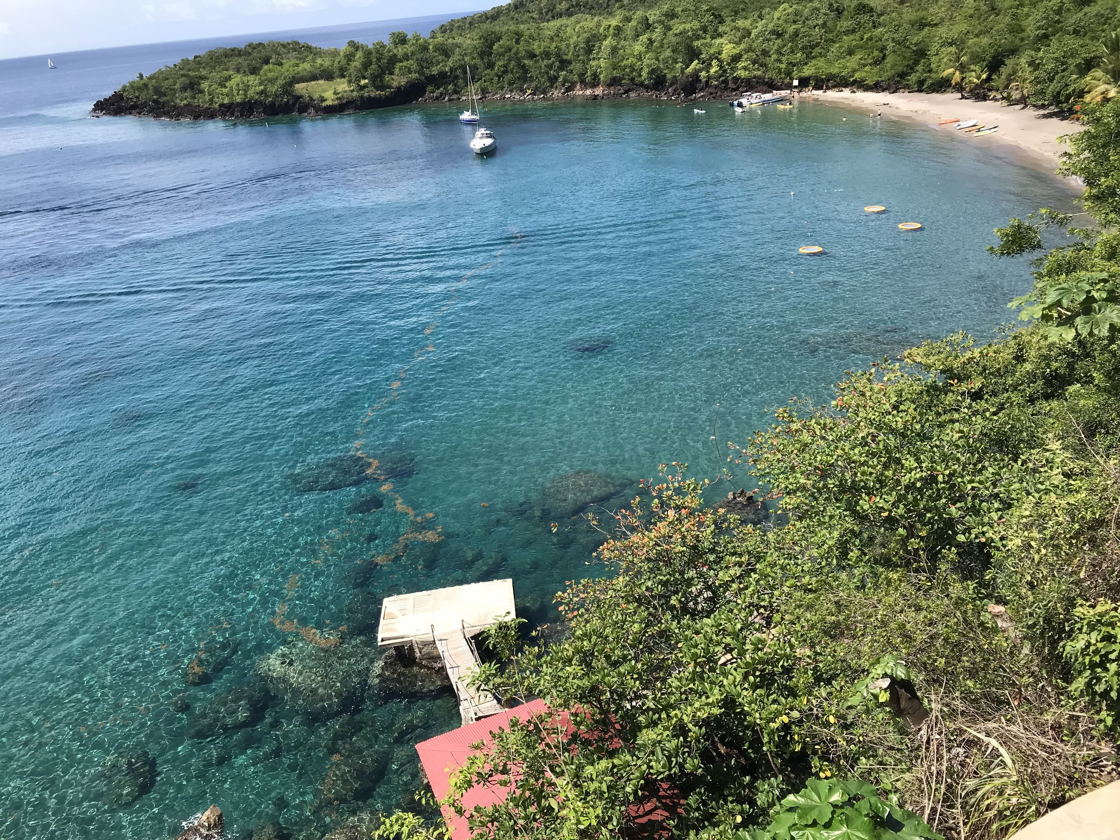Una zona costera con agua azul cristalina, barcos y una playa.