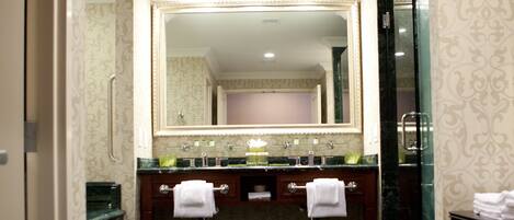 A hotel bathroom with a large mirror, two sinks, and a tiled floor.