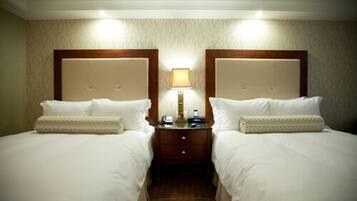 A hotel room with two beds, a nightstand with a lamp, and a carpeted floor.