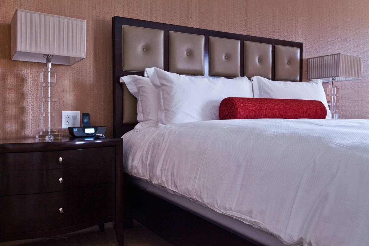 Une chambre d’hôtel avec un grand lit, une table de chevet avec une lampe et un téléphone fixé au mur.