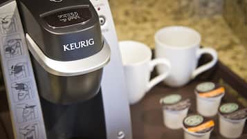 A Keurig coffee maker with a tray of disposable coffee cups and a manual.