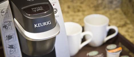 A Keurig coffee maker with a tray of disposable coffee cups and a manual.
