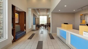 A modern hotel lobby with a reception desk, seating area, and a view of the dining space. - Holiday Inn Express West Sacramento by IHG (West Sacramento)