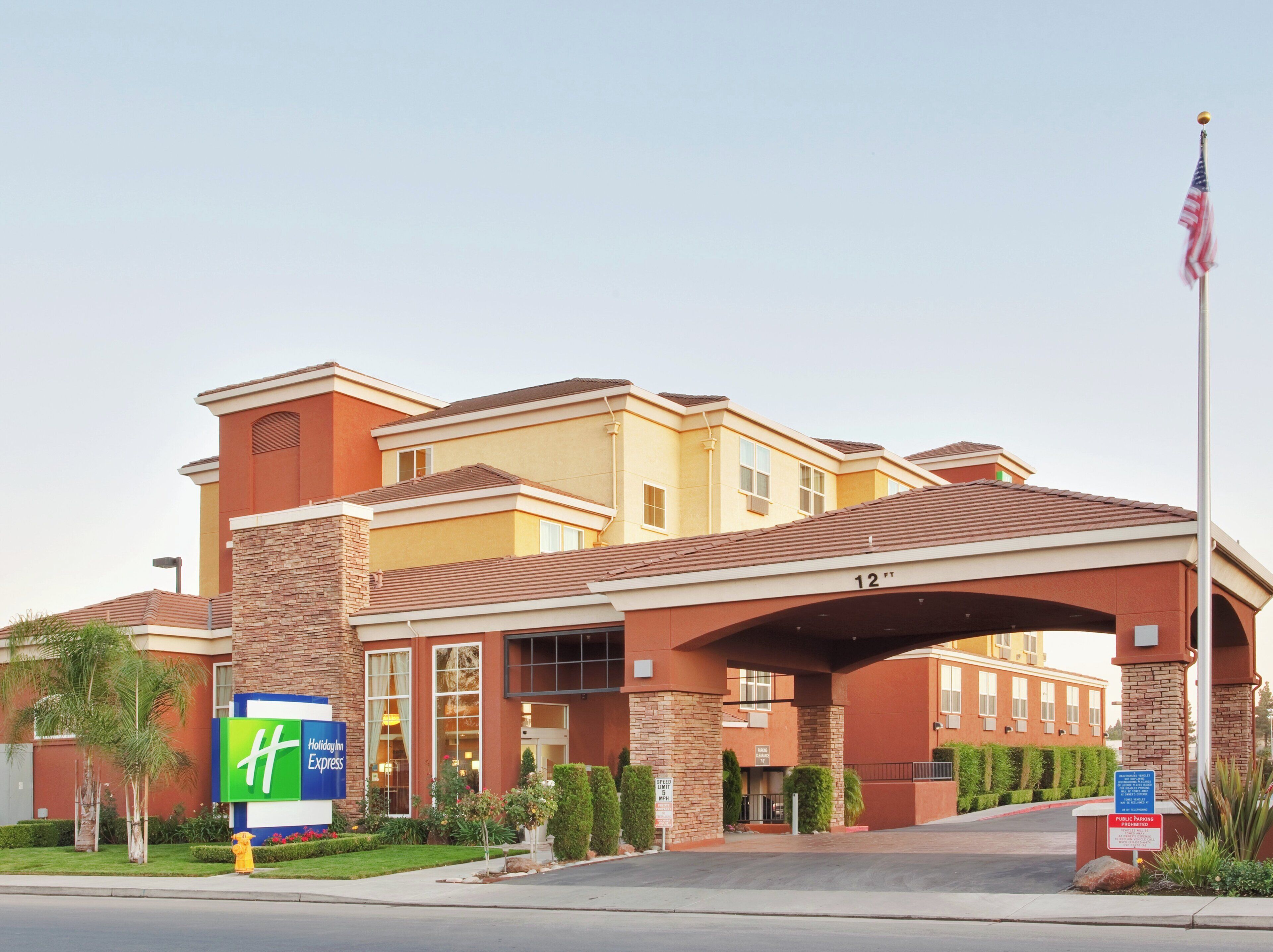 Ett Holiday Inn Express-hotell med en fasad av tegel, en överbyggd entré och en flaggstång med den amerikanska flaggan.