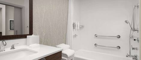 A modern bathroom with a white sink, vanity, and bathtub.