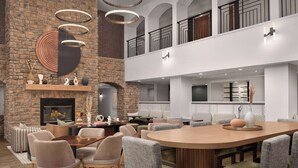 Uma sala de jantar moderna com uma grande mesa oval, cadeiras acolchoadas e uma lareira de pedra.